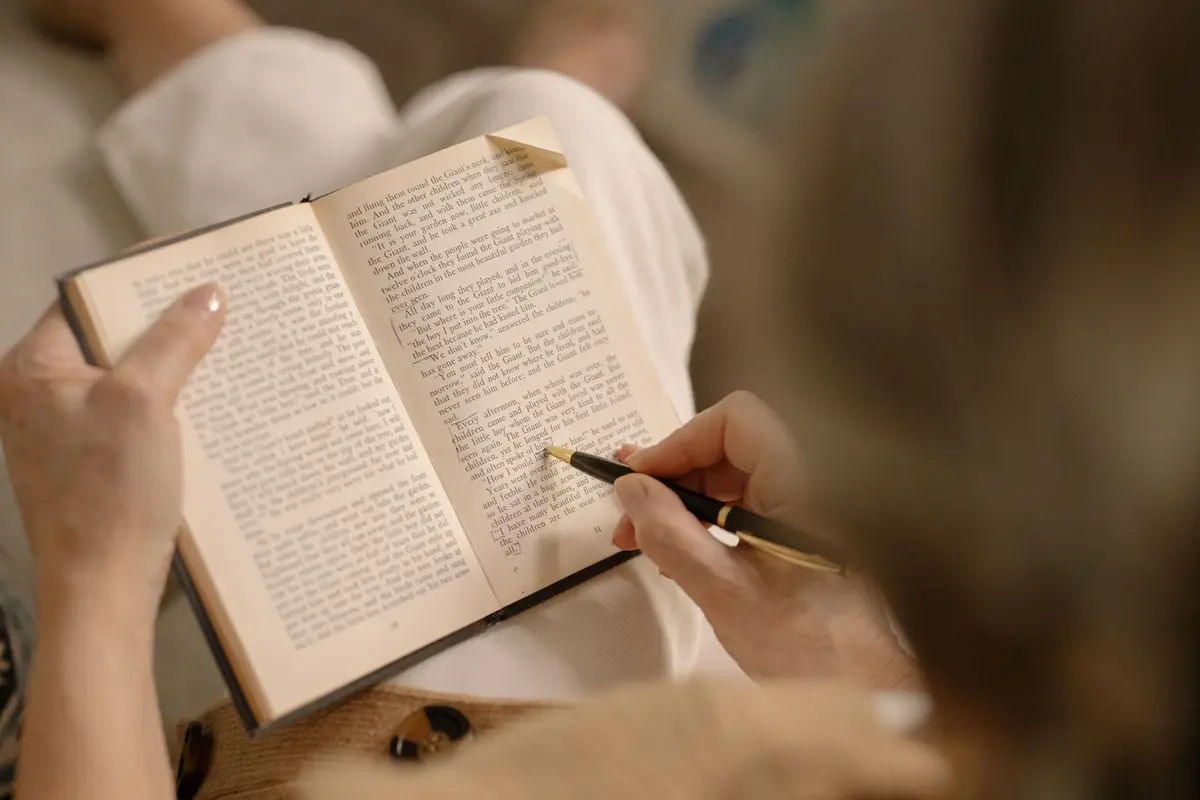 Woman reading a book and underlining passages with a pen