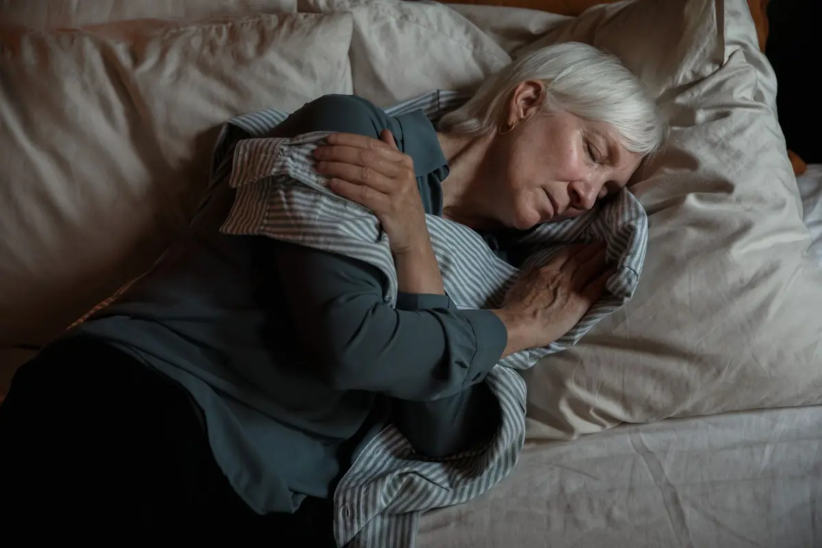 Woman in her 60s sleeping peacefully on her side in bed