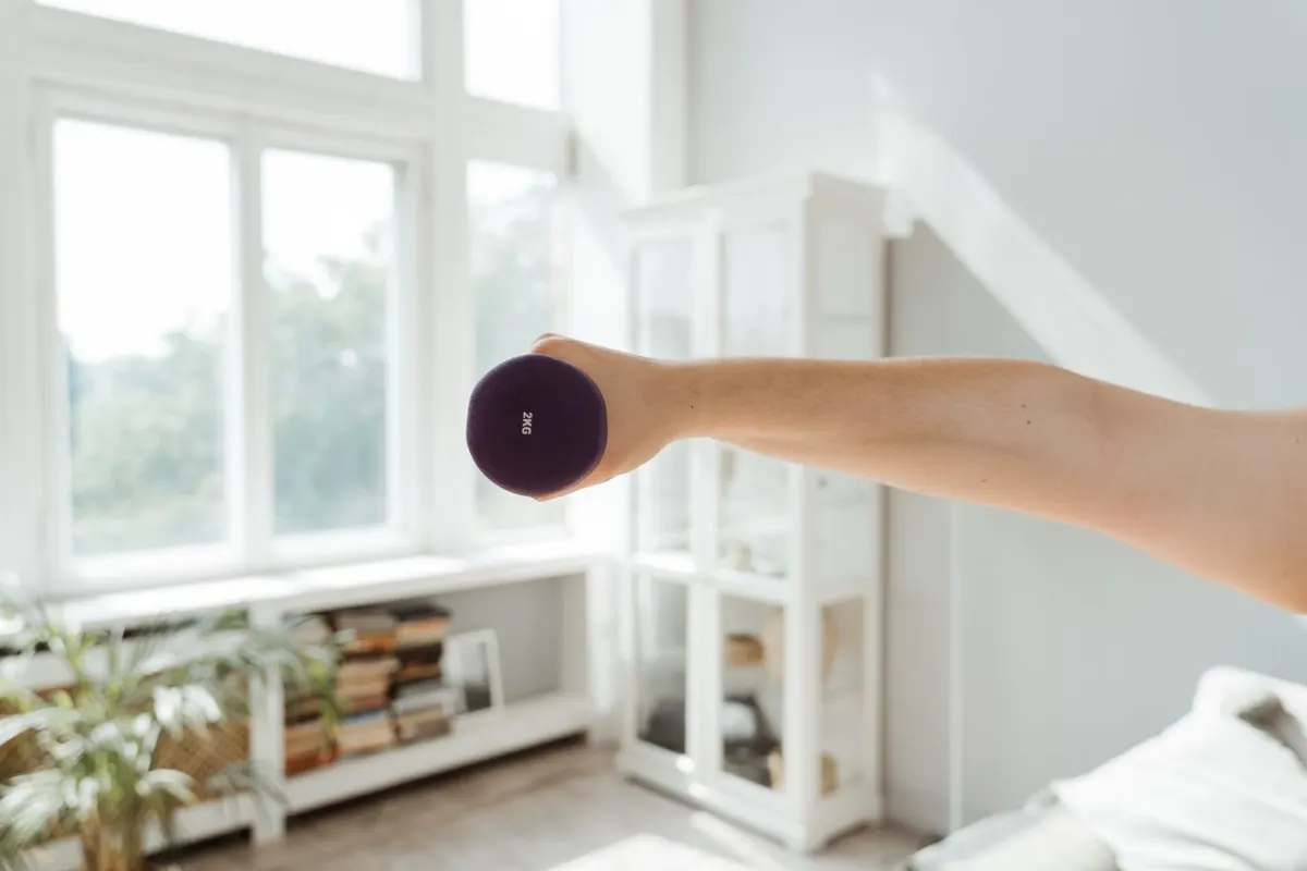 Hand lifting a dumbbell in a sunlit living room