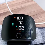 NovaMedic Pro monitor charging with a cable next to its wrist cuff