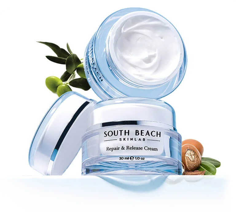 Jars of Repair & Release Cream styled with an olive branch and argan nuts