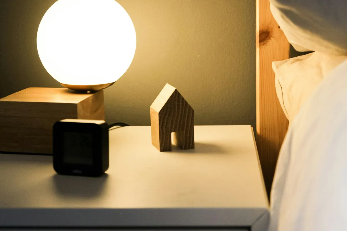Bedside table at night with a glowing lamp and a small digital clock
